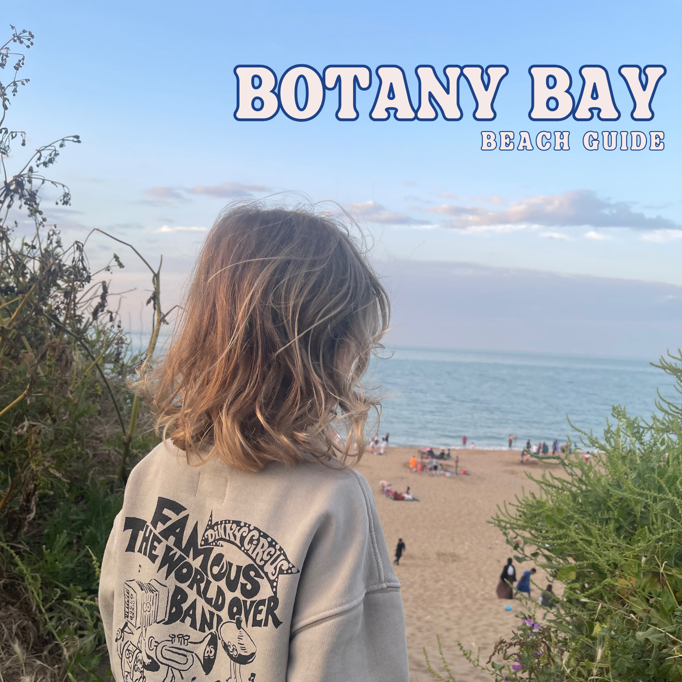 A long-haired child looks out over the sand at Botany Bay to the sea at dusk